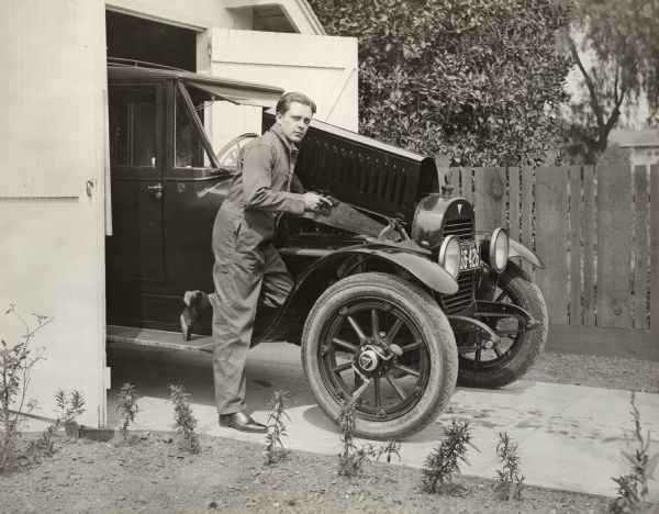 Silent film actor Niles Welch is apparently using a wood saw on the engine of a 1918 Hudson Super Six touring limousine. Other carpenter's tools--a plane and a brace drill--are also close at hand. The intention of the photograph is certainly humorous.

Original caption:
"The attention of the Society for the Prevention of Cruelty to Automobiles is respectfully invited to this picture."