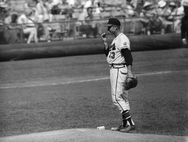 Milwaukee Braves pitcher Lew Burdette standing on the pitcher's mound in a game against the Chicago Cubs at County Stadium, June 8, 1959.  Burdette was known for his fidgety behavior between pitches and was often accused of throwing a spitball.