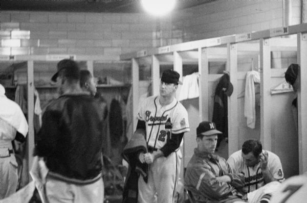 A view of the Milwaukee Braves' locker room during the 1957 pennant race. Players (left to right) are unknown (back to camera), Henry Aaron, Warren Spahn (removing jacket), Andy Pafko, and Joe Adcock.