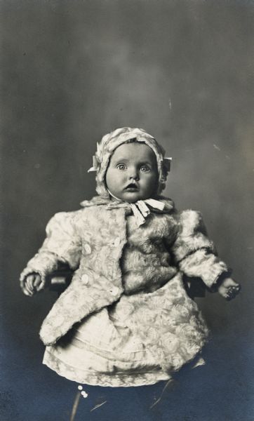 Photographic postcard of a studio portrait of Dorothy Zander as an infant dressed in a white fur coat and bonnet.