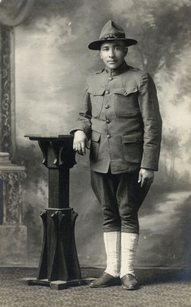 Studio portrait of Gustov Kohl, possibly dressed in a World War I uniform, in front of a painted backdrop.