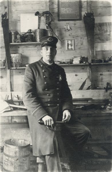 A police officer sitting on a stool in a woodshop.