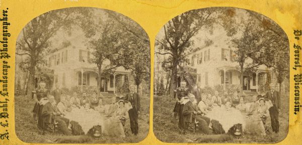 On the left, Jakob Ottesen is holding a long-stemmed pipe, and behind him a ladder is leaning against a tree. At his feet, a large dog is stretched out. The frame house behind the group is surrounded by large trees, and vines have been trained to grow on a porch that has some carpenter's lace.