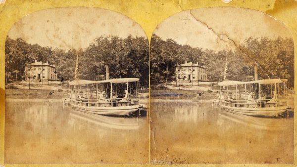 People seated in a small steamboat tied at a pier on a lake. A flag flies from the bow and there is a two-story frame house on the shore. This photograph may have some connection to the Chicago Traveling Club.