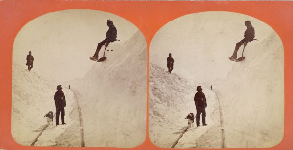 Winter scene with three men and a dog on railroad tracks, also a man in the far background. Two of the men are up on the snowbanks with shovels. "The Grand and Majestic Snowbanks on the Madison and Portage Railroad, 24th of March, 1875," possibly one of four views of "15 to 30 ft. high snow-banks" in Dahl's 1877 "Catalogue of Stereoscopic Views."