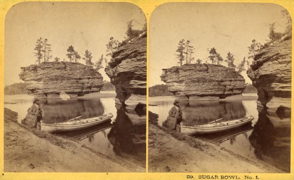 A man stands on the shoreline with a boat near the rock formations in the Sugar Bowl.