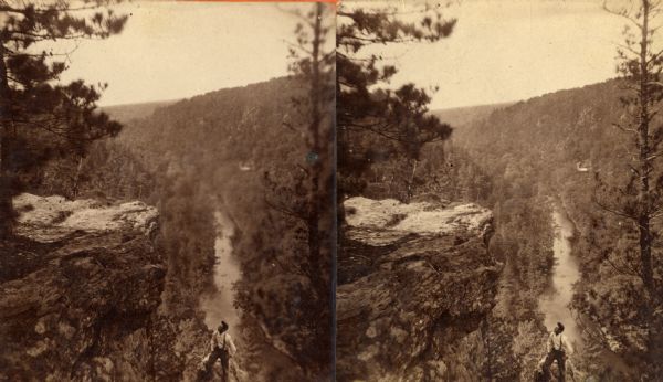 A view of a valley possibly in or around Devil's Lake. A man is visible in the foreground, hiking up the steep incline of the valley.