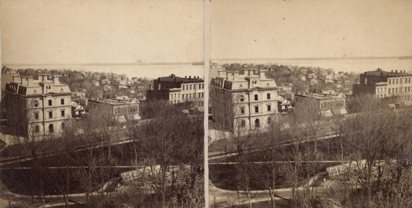 Caption on reverse side of stereograph reads, "Governmental buildings, Wisconsin Conservatory of Music and Hospital over Lake Mendota-looking from Capitol Park."  Large building on the left is the Federal Post Office and Courthouse built in 1871.  The building on the far right is the R.S. Bacon Block (later Ogden's Block) built in 1856.  The  hospital reference is probably to "Mendota" Insane Asylum across the lake.