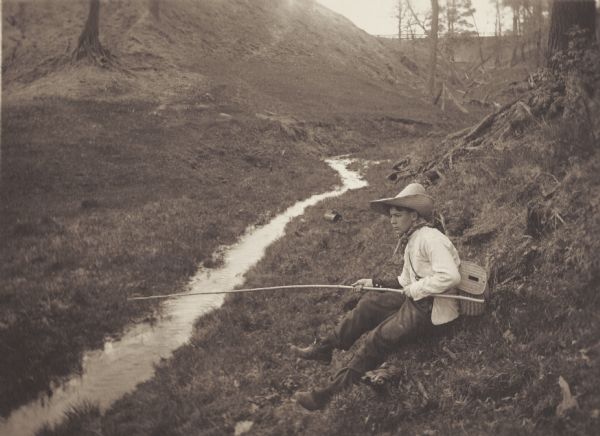 Henry A. Dahl, member of the Menomonie High School class of 1905, depicted as a fisherman. Pictured with a long wooden pole and a straw hat. Part of a yearbook created by classmate Albert Hansen, based on a class prophecy theme.