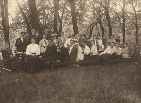 Group portrait of the senior class at Menomonie High School from 1905, having a group breakfast at Riverside Park. Part of a yearbook created by classmate Albert Hansen, based on a class prophecy theme.