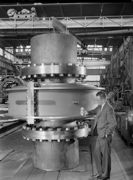 Man standing near spacer coupling that Chicago Bridge and Iron-East Chicago Industry later purchased and Inland Steel later used. Falk caption reads, "3340 spacer coupling per assembly, drawing number 416082."
