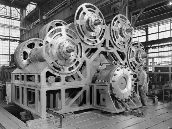 Falk caption reads, "Forward end view of partially assembled unit; shows quill shaft bearings and clutch drive discs." The final product was purchased by Sun Shipbuilding and Dry Dock Company. Male employee in photograph is R. Gosh.