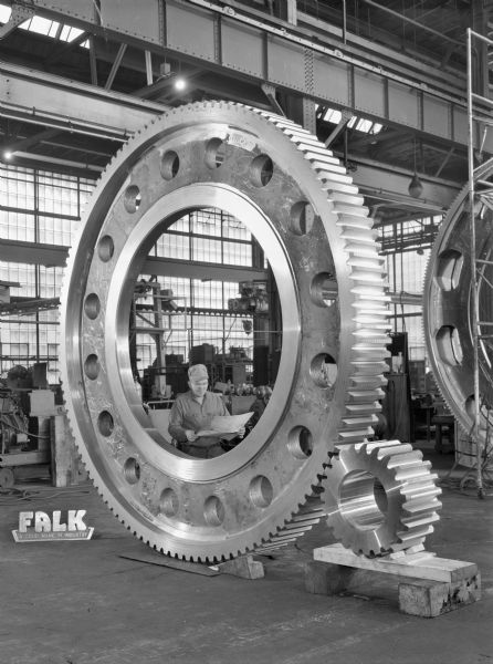 This maxipress purchased by The National Machinery Company. Falk caption reads, "6000 ton maxipress, 23-120T .7854DP (4 inch CP), 16 inch face. Gear: alloy steel casting, 265-305 Bhu (Drawing 329796). Pinion: alloy steel forging, 310-350 Bhu (Drawing 329795)." Male employee in photograph is Tony Pietraszwski.