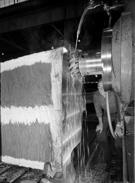 Split ring gear that was purchased by Allis Chalmers and used by Duval. Falk caption reads, "Milling Splits." Male employee in photograph is Wilbur Keen.