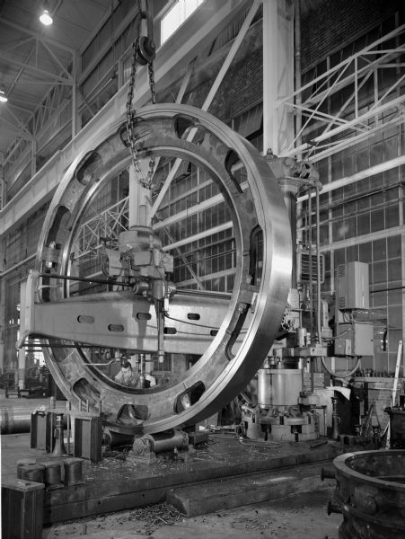 Original Falk caption reads, "Radial drilling on large split ring gear..." part of a photo and slide series for Engineering. Male employee in photograph is Ray Puls."