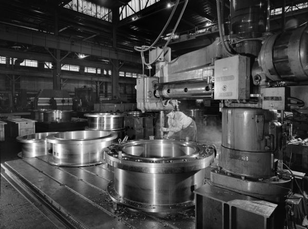 Gear coupling that was later purchased by Mesta Machine and used by Republic Steel. Original Falk caption reads, "84 inch hot strip mill, 300 G sleeve being drilled and reamed on machine number 2109 in Shop 4." Man in photograph is Eugene A. Kein.