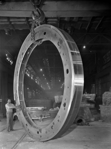 Paper mill debarker drum that was purchased and used by the Manitowoc Shipbuilding Company. Man in photograph is unidentified.
