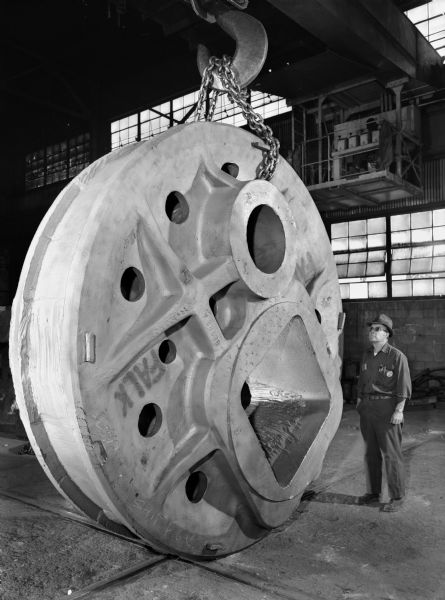 View of a cam that is a component of a 185 cubic yard Walkray Dragline that was purchased and used by Bucyries-Erie Company. An individual cam weight 51,200 pounds. Male employee in photograph is Frank Chovanec.
