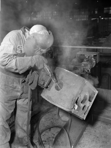 Man welding a 0200R Mixco. Falk caption reads, "Shows stick welding of housing wrapper inside."