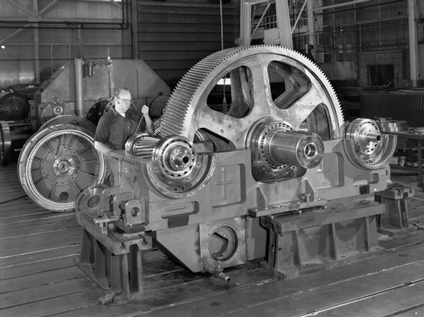 Twin pinion that was a later component of a tug on a controllable pitch propeller. This product was purchased by the Electro-Motive Division of the General Motors Company. Male employee in photograph is Al Sasada.