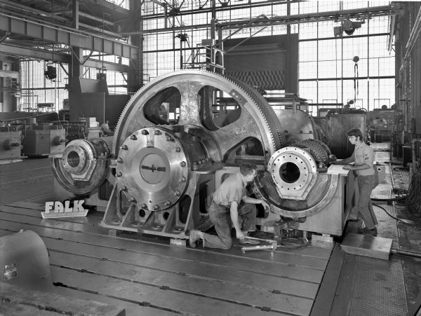 Two pinion combining gear that is a component of a main propulsion system. This product was purchased by Fairbanks Morse and used by Falcon Tankers. Original Falk caption reads, "Main propulsion 35,000 DWT tanker. Cover off views... see Engineering File for exact details." Male employees in photograph are Laurence Thibault and Harold Neske.