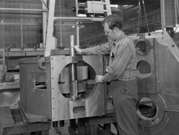 Male employee, Timothy Burton, inspecting a drive agitator. This product was purchased by Coppus Engineering Corporation and used by E.R. Squibb and Sons. Falk caption reads, "This unit is drive by a turbine at 3600 rpm input speed with ratio of 37.53:1."