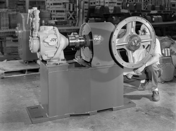 This product was purchased by Allis Chalmers and used by Kennecott Copper. Falk caption reads, "5CB3-10 BS speed reducer, ratio 7.394:1 with rifle drilled LSS and fast number 3 hs coupling, complete with bedplate for Joy Manufacturing. Air motor, 20 HP, 700 rpm, also Fawick 18CB500 clutch brake assembly on LSS." Male employee in photograph is George Tinger.