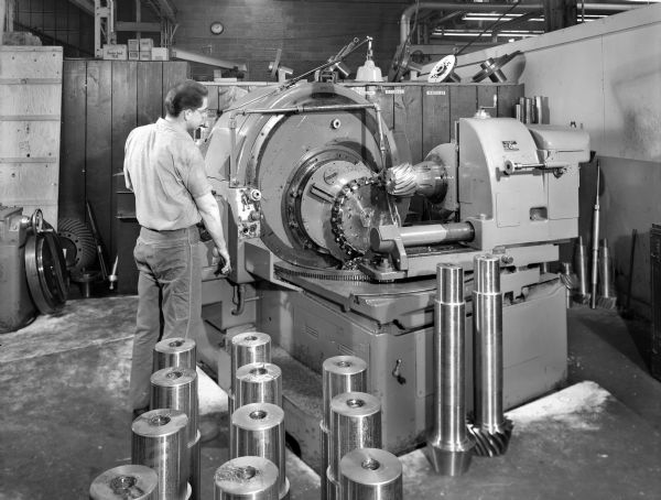 Original Falk caption reads, "Largest bevel gears manufactured by Falk to date. This photo taken in Shop 2." Male employee in photograph is Leonard Bartagewiz.