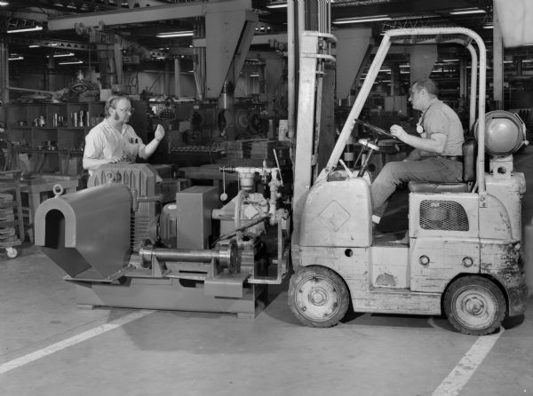 Two employees, Bob Weiss and Clyde Tetzloff, attend to a drive that was purchased by Babcock and Wilcox Company and used by AEP Service Corporation. Falk caption reads: "The subject drives will be used as maintenance inching drives on the Babcock and Wilcox MPS 89 coal pulverizers. A total of four assemblies were supplied on model numbers, 7-341672 and 7-341816. The ASU 10 radicon unit is driven by an Ingersoll Rand radial piston air motor. Included in the drive is a spring set air release brake, Falk couplings, and air filter and lubricator and a quick connect disconnect air fitting. The entire drive is designed to be mobile and can be moved and positioned at different pulverizers by a fork lift truck. The customizer insisted on the air motor as the prime mover, because air pressure was available throughout the plant. It can quickly and easily be connected and disconnected to the air supply because its single lever control provides variable speed in both directions of rotation."