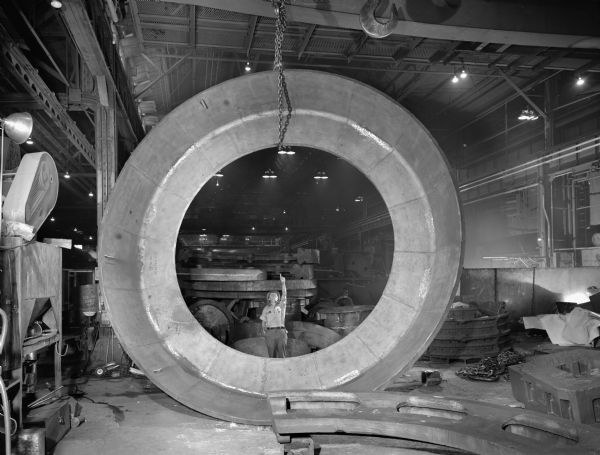 View of a lip ring casting that is a component of a basic oxygen furnace. This particular unit was purchased by Chicago Bridge and Iron of Greenville, Pennsylvania. Falk caption reads, "Pouring lip for basic oxygen furnace. Weight is 25,000 pounds. It will be welded to shell of furnace at open end which contains the brick lining. Capacity of furnace is about 250 tons. Picture taken for possible photo caption release for news and trade papers." Male employee in photograph is Francis Chovanec.