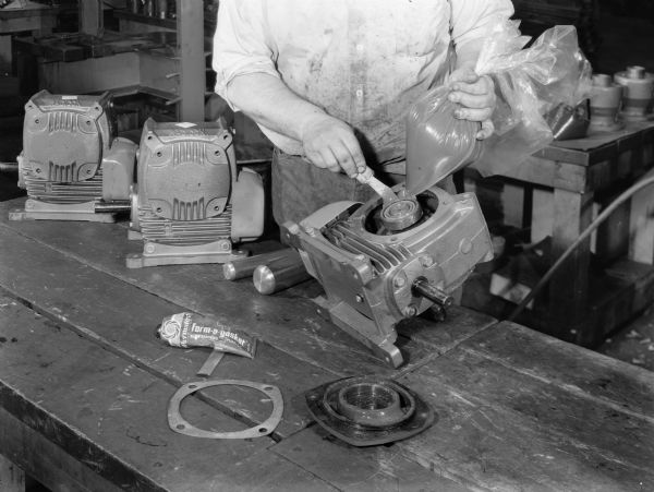 Original Falk caption reads, "These pictures taken to illustrate a procedure to allow saving and reusing Tivela lube during service or repair operations on adaptable size lube for life worm gear reducers." Male employee in photograph is Robert Wein.