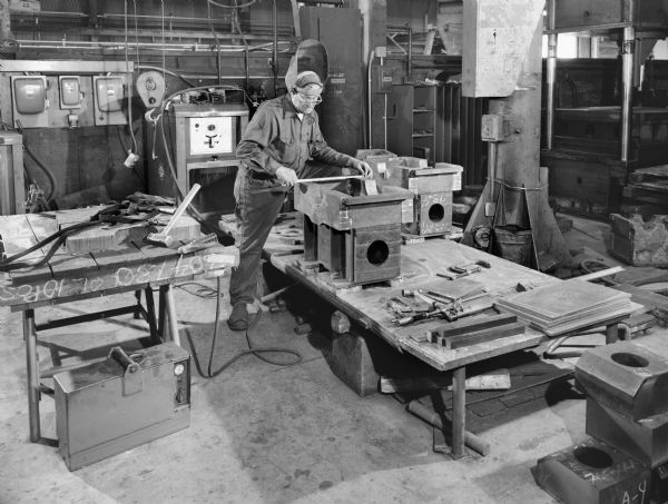 Male employee, Harold Ladwig, in the Weld Shop. Original Falk caption reads, "A series of pictures taken in Weld shop to illustrate steps in the manufacture of Type B worm gear drives."