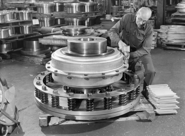 Male employee, Jake Gemmel, attending to a FT coupling. Original Falk caption reads, "These pictures taken to illustrate FT coupling size... this is the largest FT we [Falk] have produced in recent times."