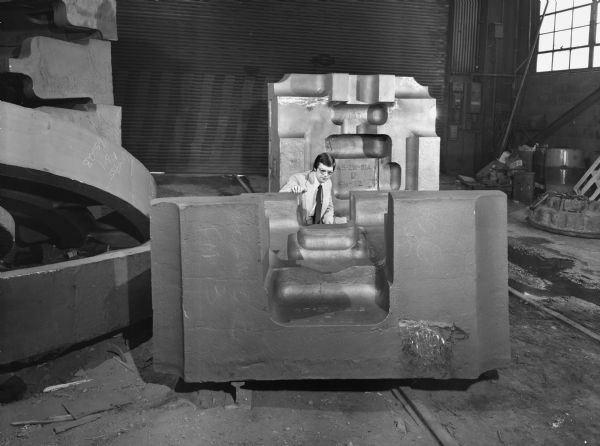 This unit was purchased by the Ford Motor Company. Original Falk caption reads, "Cover die holder block: pattern number 45ZW-51A, approximate weight 25,400 pounds, material Falk Gearalloy number 4 N and T to 269-309 BHN. Ejector die holder block: pattern number 45ZW-51B, approximate weight 29,100 pounds, material Falk Gearalloy number 4 N and T to 269-309 BHN." Male employee in photograph is William Rhody.