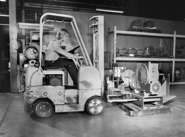 Tim Wollenziehr, a Falk employee drives a fork-lift carrying an inching drive, a later component of a coal pulverizer. This unit was purchased by Babcock and Wilcox Company and used by the Missouri Basin Power Project. Original Falk caption reads: "Special inching drive package includes 100BUR-197.3 special bed plate, Ingersoll Rand EE SUM air motor, Carlson 7 SB200 air brake, 15G62 brake wheel coupling, L.S. shaft assembly (floating) with 30G52 and 25G52."