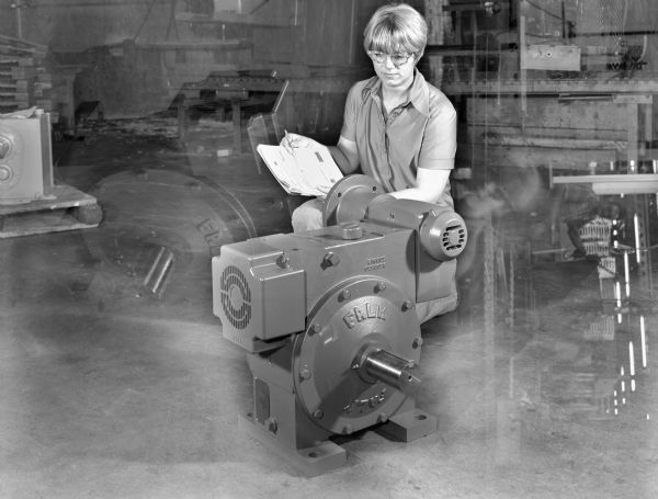 Lynnette Hartwig, a Falk employee, inspects a gear. This unit was later purchased by the Wisconsin Bearing Company. Original Falk caption reads: "Illustrates "C" flange adapter on Falk type B double reduction worm gear reducers." Double exposure.
