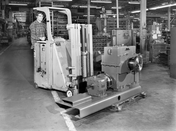 James Blaesius, a Falk employee, operates a fork-lift that carries a component of a conveyor drive. This unit was purchased by Kaisers Engineers and used by Asarco Incorporated of El Paso, Texas. Original Falk caption reads: "140 BU worm gear with 11 foot coupling and 40 RC reducer on bed plate with 150T LS coupling on worm. See Engineering File for exact details."