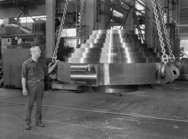 Theodore A. Lutzen, a Falk employee, guides a pipe cap as it is being lowered. This unit was purchased by Vulcan Iron Works. Original Falk caption reads, "Pipe cap: pattern number 29A-1000-1, drawing number D12730, approximate weight 78,000 pounds, material Falk Gearalloy number 1 Q and Temper 200BHN, project-oil drilling in Indonesia."