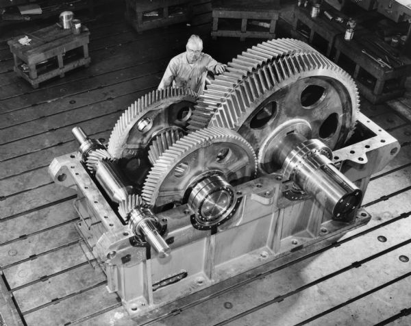 Mel Zdroik, a Falk employee, attends to a copper ore conveyor that was used by the Codelco Company of Chile, South America. Original Falk caption reads, "Part of a series of planned photos of ten orders (model numbers 8-175221 through 230) for installation in a Chile Copper Mine. See Engineering File for exact specifications. These photos were taken by Sundstrand and these black and white photos were made from color negatives furnished by Sundstrand. Color photos: 45NF5155, 56 and 57."