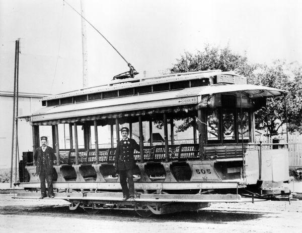 Two streetcar engineers pose with a streetcar. Original Falk caption reads, "Photos borrowed from Milwaukee County Transport for use in brochure 850801. Originals returned to County. Milwaukee streetcars."