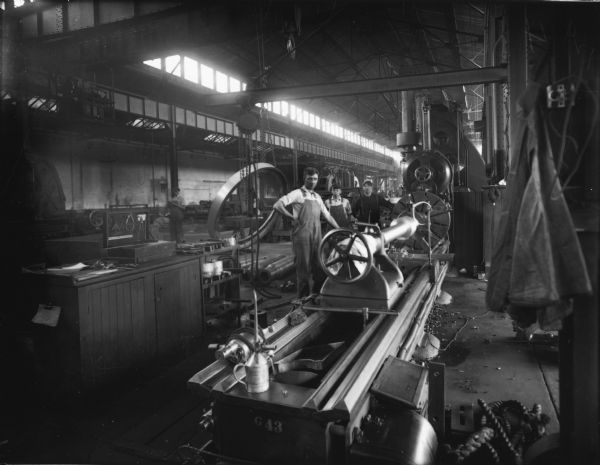 Three Falk employees attend to a large machine in the foundry. Original Falk caption reads, "Centennial historical photos of old negative which could be lost forever. Probable dates prior to World War One."