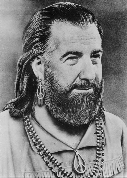 A poster with a retouched portrait of Vice President Spiro Agnew dressed as a hippie. He has a beard, moustache, and long hair. He is wearing a fringed shirt with a peace sign, matching earring, and a beaded necklace. On the front of the poster a handwritten note describes it as a "dedication page" and that it was "sold by Hippies." There is also a price of 25 cents. On the back of the poster, additional handwritten notes read, "Sold by Hippies all around the streets on 4-XI" and "The MPPC is Dedicated to Spiro Agnew (until he's convicted)."
