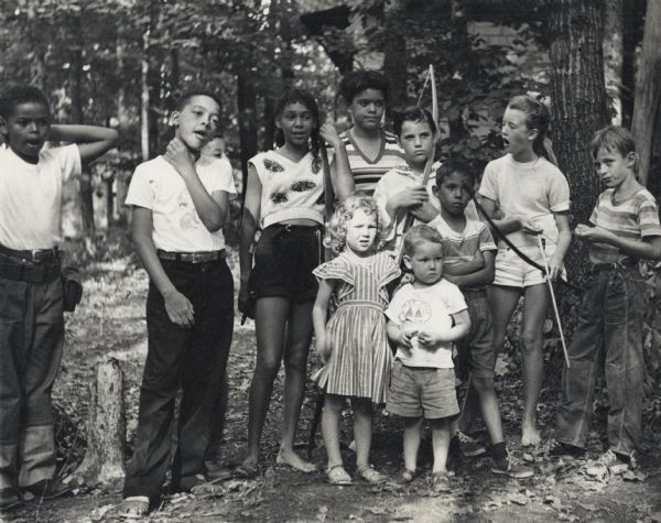 Group portrait of eleven children practicing archery in the woods of the Highlander Folk School. Part of the Koinonia Children's Camp program. Fourth from right, Charis Horton. Next to her on left is Cheryl Parker.
