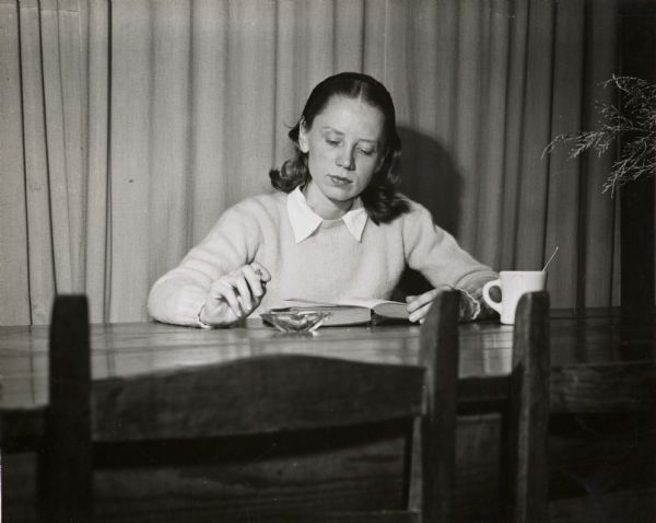 Catherine Winston, a staff member at the Highlander Folk School, reading a book and smoking a cigarette.