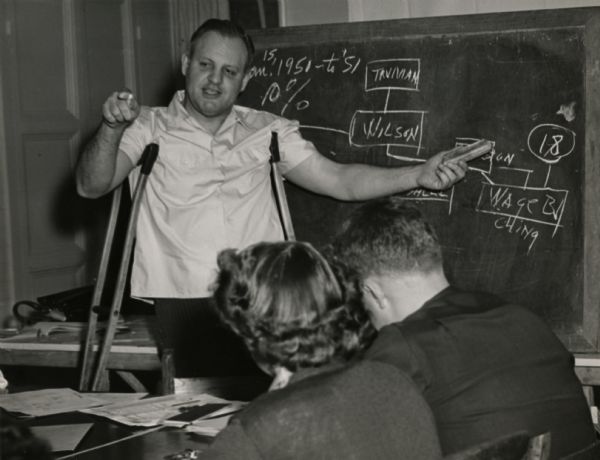 George Guernsey, with crutches, teaching CIO students at a Highlander Folk School workshop.  Chalkboard makes reference to Woodrow Wilson and Harry Truman.