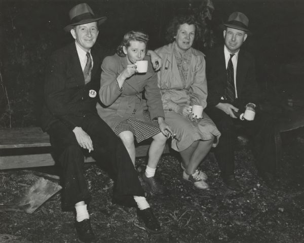 A group of hosiery workers sitting on a bench, smoking cigarettes, and drinking coffee.