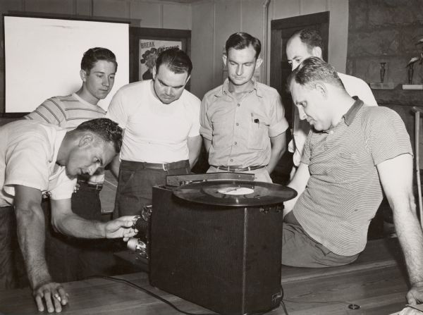 CIO workshop at Highlander Folk School, featuring George Guernsey, extreme right.  A group of five men gathered around a record player.