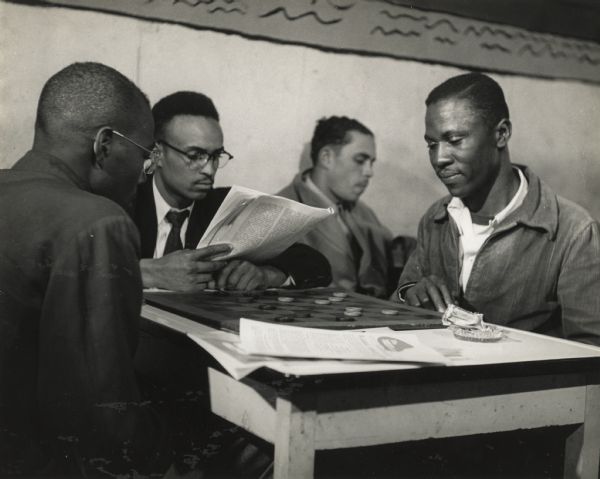 Two men playing checkers, while another reads a journal, taking a break from a Civil Rights Workshop at Highlander Folk School.