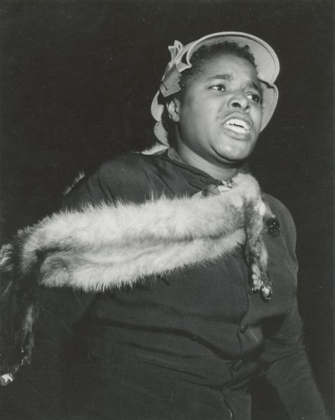 A female, African American Civil Rights activist wearing a fur pelt attending a meeting.