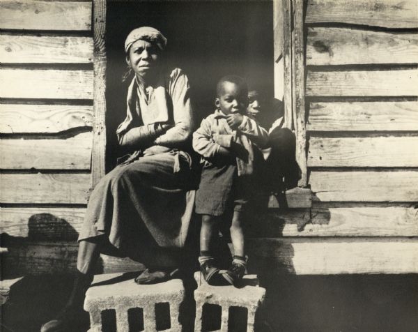 An African American woman with two children on the porch of a house on Johns Island.